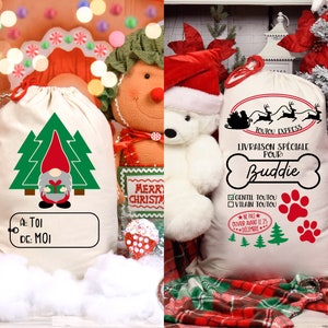 May include: Two white canvas Christmas gift bags with different designs. One bag features a gnome with a red hat and a green tree. The other bag features a bone with the text "Livraison Sp&eacute;ciale Pour: Buddie" and a paw print.