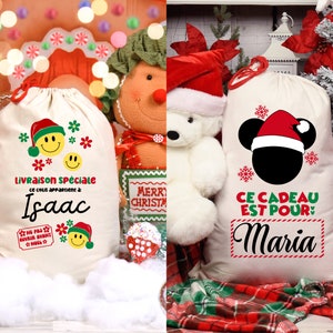 May include: Two white Christmas gift bags with red and green trim. One bag has a smiling face with a Santa hat and the text "Livraison sp&eacute;ciale ce colis appartient &agrave; Isaac". The other bag has a Mickey Mouse head with a Santa hat and the text "Ce cadeau est pour Maria".