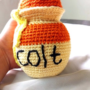 May include: A crocheted orange and yellow jar with a white lid and the word "Salt" embroidered on the front.