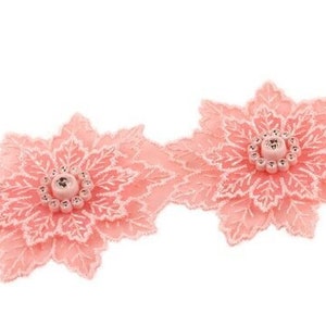 Könnte beinhalten: Rosa Spitzenborte mit floralem Muster und einem Perlenmittelpunkt. Die Borte ist perfekt, um jedem Projekt einen Hauch von Eleganz zu verleihen.