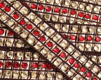 Könnte beinhalten: Nahaufnahme einer dekorativen Borte mit einem sich wiederholenden Muster aus roten und goldfarbenen Strasssteinen, die in einem braunen Gitter angeordnet sind. Die Borte wird wahrscheinlich zum Verzieren von Kleidung oder Bastelprojekten verwendet.