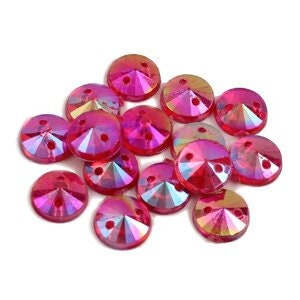 May include: A group of 15 pink iridescent sew-on flatback rhinestones with two holes.