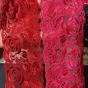 May include: Two pieces of red and pink lace trim with a floral design. The lace is delicate and intricate, with a mesh background.