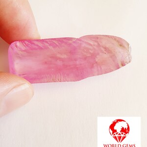 May include: A large, pink, rough-cut gemstone with striations and a translucent appearance.