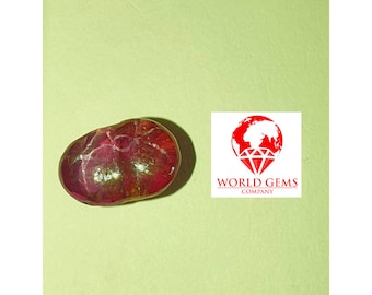 May include: A red gemstone with a smooth, oval shape. The gemstone has a slight shimmer and is set against a light green background.