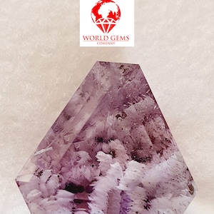 May include: A purple amethyst crystal with a unique, feathery formation. The crystal is faceted and has a geometric shape.