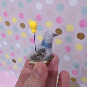 needle felt miniature pigeon with a mini balloon made out of clay