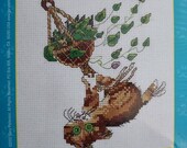 Cross stitch kit by Janlynn is a picture of a cat hanging upside down from a planter.