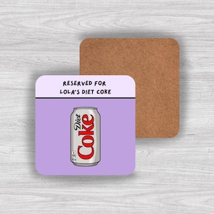 May include: A square coaster with a light purple background featuring a silver Diet Coke can illustration and the black text RESERVED FOR LOLA'S DIET COKE. The coaster has a cork backing and a smooth top surface with rounded corners.