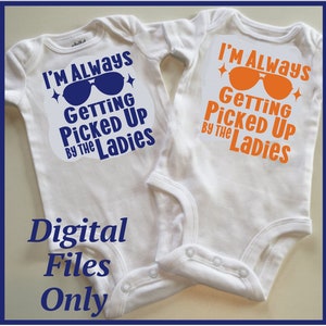 Puede incluir: Dos bodies blancos para bebé con un estampado gráfico azul y naranja. El texto en los bodies dice "I'm Always Getting Picked Up By The Ladies".