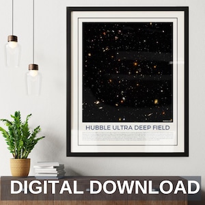 May include: A black framed print of the Hubble Ultra Deep Field, a photograph of a small patch of space containing thousands of galaxies. The print is hanging on a white wall above a wooden cabinet with a potted plant and books.