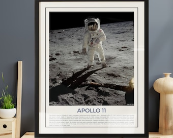May include: Framed print of the Apollo 11 mission. An astronaut in a white spacesuit stands on the moon's surface, casting a long shadow. The print has a black frame and includes the text "APOLLO 11" at the bottom.