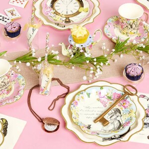 May include: Alice in Wonderland themed party supplies, including plates, cups, napkins, and a key. The plates feature a floral design with Alice and a quote from the book. The cups have a floral design with a bird and a rabbit. The napkins have a floral design with a clock. The key is gold and has a floral design.