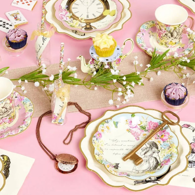 May include: Alice in Wonderland themed party supplies, including plates, cups, napkins, and a key. The plates feature a floral design with Alice and a quote from the book. The cups have a floral design with a bird and a rabbit. The napkins have a floral design with a clock. The key is gold and has a floral design.