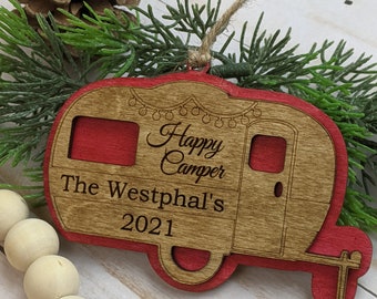 Könnte beinhalten: Roter und brauner Holzanhänger-Weihnachtsbaumschmuck mit dem Text "Happy Camper" und "The Westphal's 2021" eingraviert.