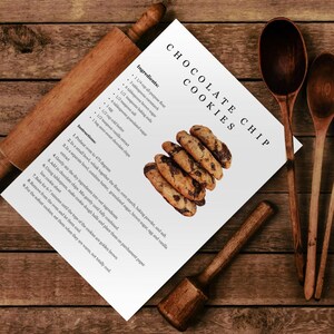 Puede incluir: Una tarjeta de receta imprimible para galletas con chispas de chocolate con una pila de galletas reci&eacute;n horneadas en el fondo.