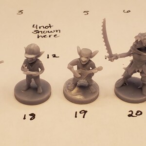 May include: A collection of unpainted miniature fantasy figures, including goblins, a bug-like creature, and a figure with a hat. Each figure is on a round base. The figures are numbered 16, 17, 18, 19, 20, 21, and 22.