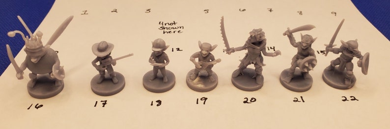 May include: A collection of unpainted miniature fantasy figures, including goblins, a bug-like creature, and a figure with a hat. Each figure is on a round base. The figures are numbered 16, 17, 18, 19, 20, 21, and 22.