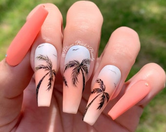 May include: Coral-coloured, long, square artificial nails with a beach design. The design includes palm trees, a gradient sky, and small birds. The text "Natural Light" is visible in the upper right corner.
