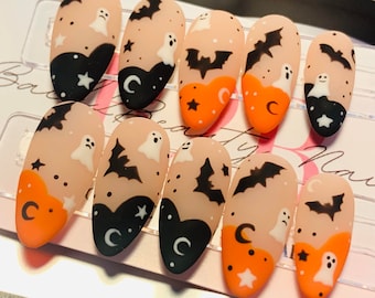 May include: Set of ten Halloween-themed press-on nails with orange, black, and white designs. The designs include bats, ghosts, stars, and crescent moons.