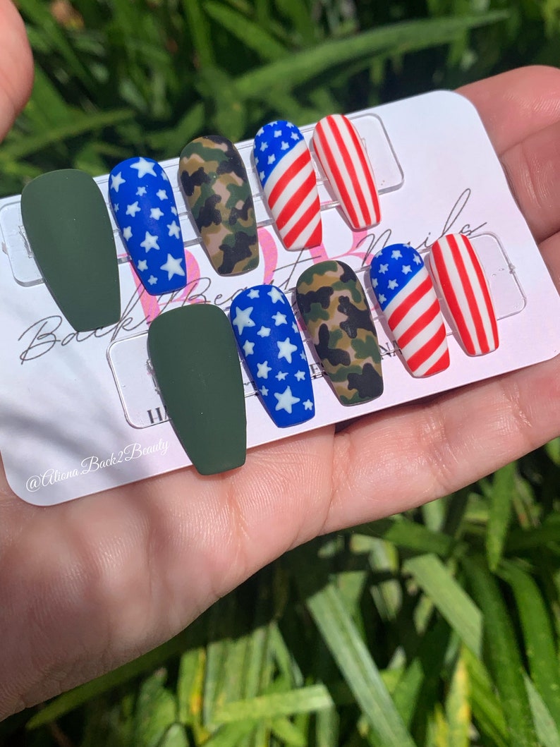 Puede incluir: Conjunto de diez u&ntilde;as postizas con tem&aacute;tica patri&oacute;tica. Las u&ntilde;as presentan un dise&ntilde;o verde, camuflaje, azul con estrellas blancas y bandera estadounidense roja, blanca y azul.