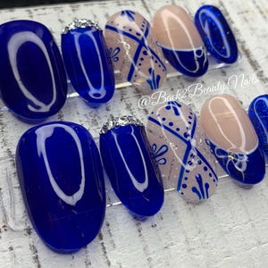 May include: Set of ten blue and white nail tips with a geometric design. The tips are oval shaped and have a glossy finish. The tips are arranged in a row on a white surface. @Back2BeautyNails