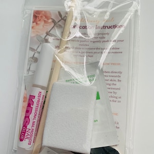 Puede incluir: Una bolsa de pl&aacute;stico transparente que contiene un juego de suministros para el arte de u&ntilde;as. El juego incluye una peque&ntilde;a botella de pegamento para u&ntilde;as etiquetada como "KDS Professional Nail Products", un empujador de cut&iacute;culas de madera, una lima de u&ntilde;as blanca, un peque&ntilde;o paquete blanco y una lima de u&ntilde;as negra. La bolsa tambi&eacute;n incluye una peque&ntilde;a tarjeta con instrucciones para aplicar el arte de u&ntilde;as.