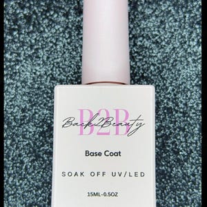 May include: A clear bottle of nail polish base coat with a pink label. The label says "Back2Beauty", "Base Coat", "SOAK OFF UV/LED", and "15ML-0.5OZ".