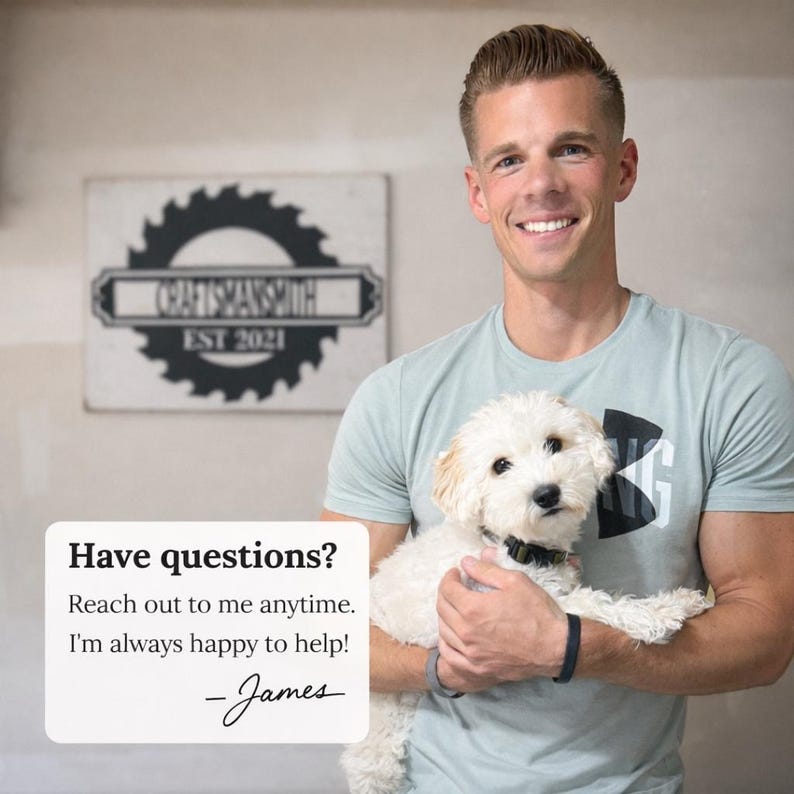 A friendly portrait of James, the craftsman behind CraftsmanSmith, smiling while holding a small white dog. In the background, a workshop sign featuring a saw blade logo and 'EST 2021' is visible. A text overlay invites customers to reach out with any questions.