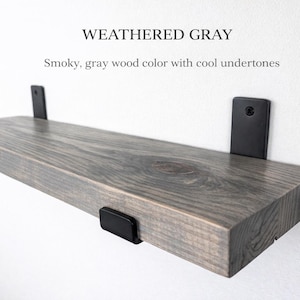 Peut inclure: &Eacute;tag&egrave;re en bois gris vieilli avec des supports en m&eacute;tal noir. L'&eacute;tag&egrave;re a une couleur de bois gris fum&eacute; avec des nuances froides. L'&eacute;tag&egrave;re est fix&eacute;e &agrave; un mur blanc. Le texte "WEATHERED GRAY" est en haut.