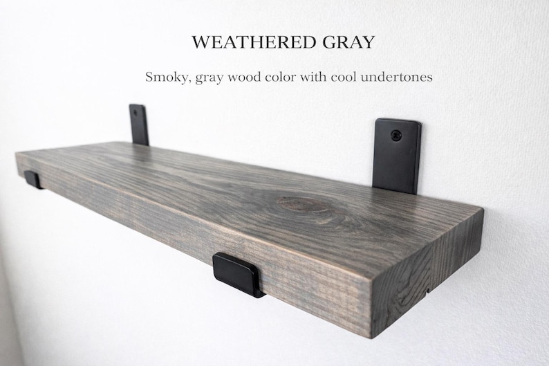 Peut inclure: &Eacute;tag&egrave;re en bois gris vieilli avec des supports en m&eacute;tal noir. L'&eacute;tag&egrave;re a une couleur de bois gris fum&eacute; avec des nuances froides. L'&eacute;tag&egrave;re est fix&eacute;e &agrave; un mur blanc. Le texte "WEATHERED GRAY" est en haut.