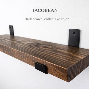 Peut inclure: &Eacute;tag&egrave;re en bois brun fonc&eacute;, couleur caf&eacute;, avec des supports en m&eacute;tal noir. L'&eacute;tag&egrave;re est rectangulaire et semble &ecirc;tre en bois massif. Le texte "JACOBEAN" et "Brun fonc&eacute;, couleur caf&eacute;" sont visibles.