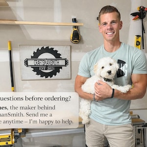 Peut inclure: Un homme tenant un petit chien blanc dans un atelier. Un panneau avec le texte "CraftsmanSmith EST 2021" est accroch&eacute; au mur. L'homme porte un t-shirt bleu clair et un short kaki. Le texte sur l'image dit : "Vous avez des questions avant de commander ? Je suis James, le cr&eacute;ateur de CraftsmanSmith."