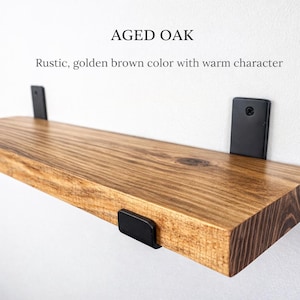 Peut inclure: &Eacute;tag&egrave;re flottante en ch&ecirc;ne vieilli avec des supports en m&eacute;tal noir. L'&eacute;tag&egrave;re est d'une couleur brun dor&eacute; chaud avec un grain de bois visible. Le texte "Aged Oak" et "Rustic, golden brown color with warm character" sont affich&eacute;s au-dessus.
