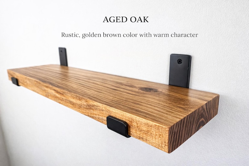 Peut inclure: &Eacute;tag&egrave;re flottante en ch&ecirc;ne vieilli avec des supports en m&eacute;tal noir. L'&eacute;tag&egrave;re est d'une couleur brun dor&eacute; chaud avec un grain de bois visible. Le texte "Aged Oak" et "Rustic, golden brown color with warm character" sont affich&eacute;s au-dessus.