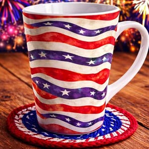 May include: A white ceramic mug with a patriotic design of red and blue wavy stripes and white stars. The mug sits on a red, white, and blue coaster, with fireworks in the background.