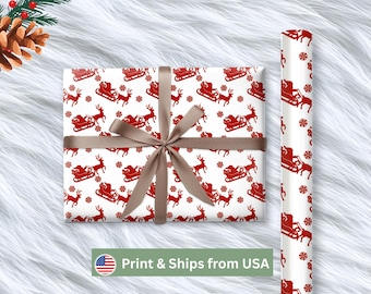 May include: White Christmas wrapping paper with a repeating pattern of red Santa in his sleigh, reindeer, and snowflakes. A wrapped gift is tied with a brown ribbon. A roll of matching paper is visible.