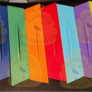 May include: Ten colorful rectangular blocks with rounded edges. Each block has a different color: pink, yellow, blue, green, orange, red, light blue, purple, yellow, and white. The blocks have a raised design with the text "Monarch Club Honeybees" on each block.