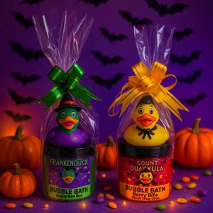 May include: Two Halloween bubble bath gift sets. One features a green and purple Frankenduck, the other a yellow Count Ouackula duck. Each set is in a clear bag with a bow, surrounded by pumpkins and sweets.