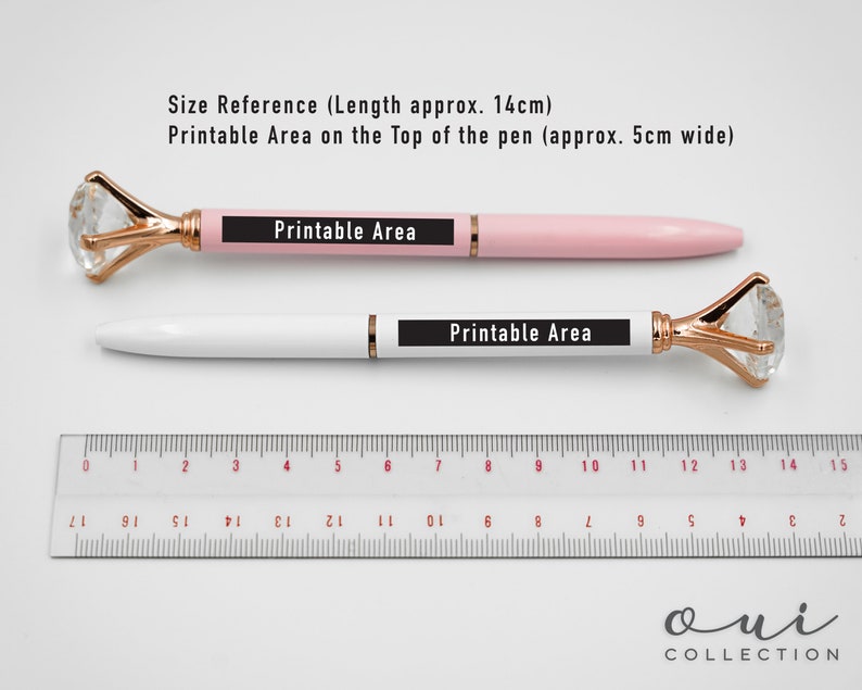 Puede incluir: Dos bol&iacute;grafos, uno rosa y otro blanco, con tapas de cristal en forma de diamante y detalles dorados. Los bol&iacute;grafos miden aproximadamente 14 cm de largo, con un &aacute;rea imprimible. Una regla est&aacute; colocada debajo. Texto en los bol&iacute;grafos: "Printable Area".