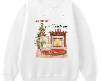 Op de afbeelding: Witte sweatshirt met een aquarel illustratie van een kersttafereel. Het ontwerp toont een versierde kerstboom, een open haard, een fauteuil en een kat. De tekst "ALL BOOKED for Christmas" is op de sweatshirt gedrukt.