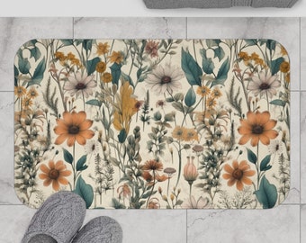 Könnte beinhalten: Eine beige Badematte mit einem Blumenmuster aus orangefarbenen, gelben und grünen Blumen. Die Blumen sind in einem zufälligen Muster auf einem cremefarbenen Hintergrund angeordnet.
