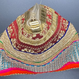 May include: A small, triangular-shaped pouch with a zipper closure. The pouch is made of a red fabric with gold embroidery and a variety of colorful trim.