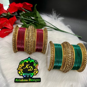 May include: Two sets of bangles, one set is maroon and the other is green. Both sets have gold accents and rhinestones.
