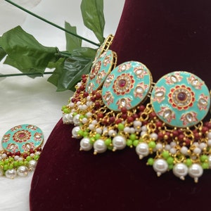 May include: A turquoise and gold choker necklace with red and white enamel detailing and pearl and green bead accents. Matching earrings with the same design are included.