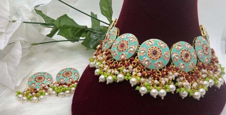 May include: A turquoise and gold choker necklace with red and white enamel detailing and pearl and green bead accents. Matching earrings with the same design are included.