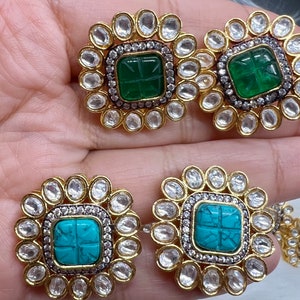 Puede incluir: Un par de pendientes de oro con una piedra cuadrada turquesa y verde engastada en un marco circular de piedras transparentes.