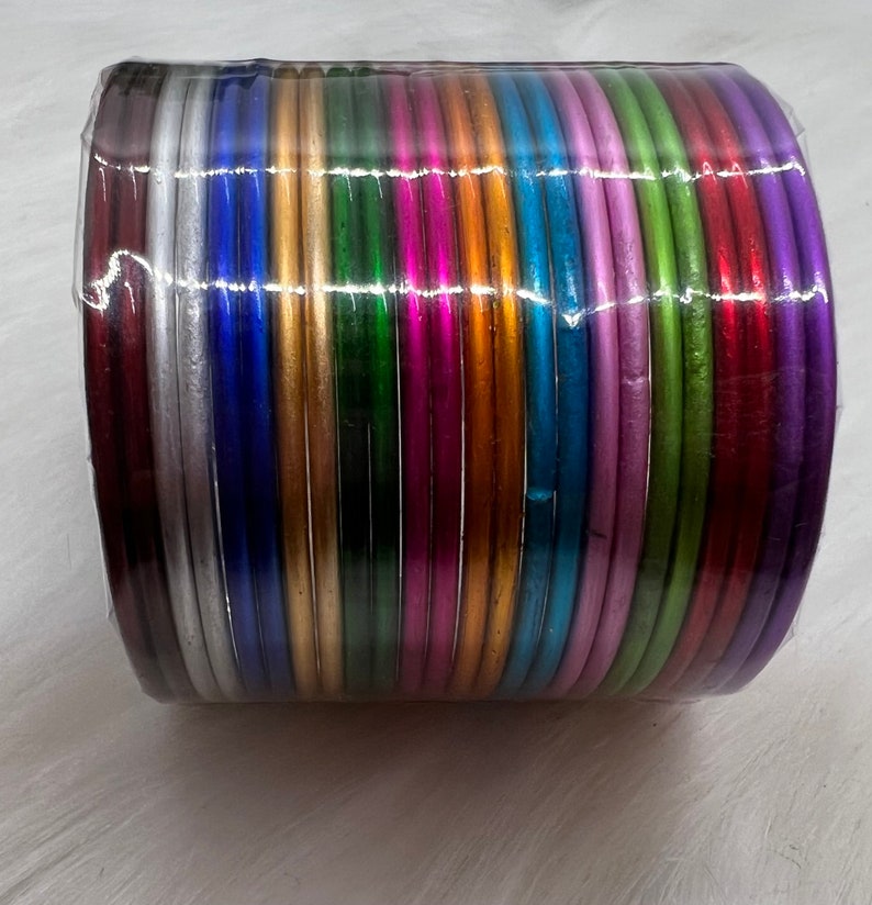 May include: A stack of colorful metal bangles in various shades of silver, gold, green, blue, purple, and red.