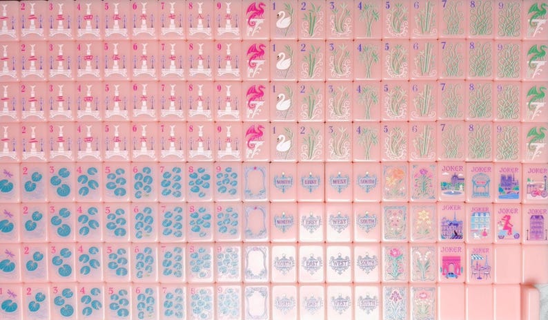May include: A collection of rectangular mahjong tiles in a soft pink hue. The tiles feature various printed illustrations including numbered sets, swan motifs, floral patterns, directional markers labeled North, East, West, South, and Joker tiles.