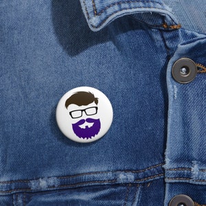 May include: White button with a cartoon illustration of a person with brown hair, glasses, and a purple beard.